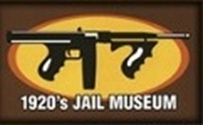 A sign that says 2 0 's jail museum with an image of a gun.