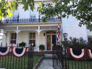 A white house with red and blue bunting on the front lawn.