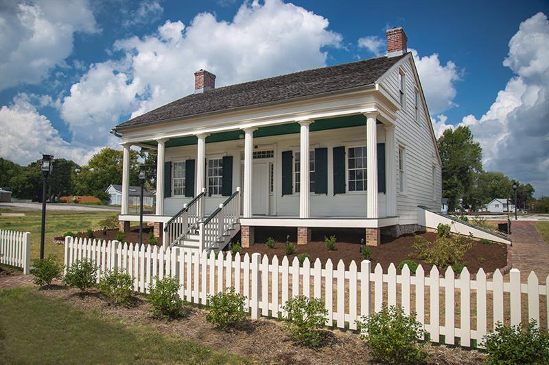 A white house with green shutters and a picket fence.