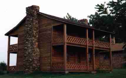 A log cabin with two levels and a porch.