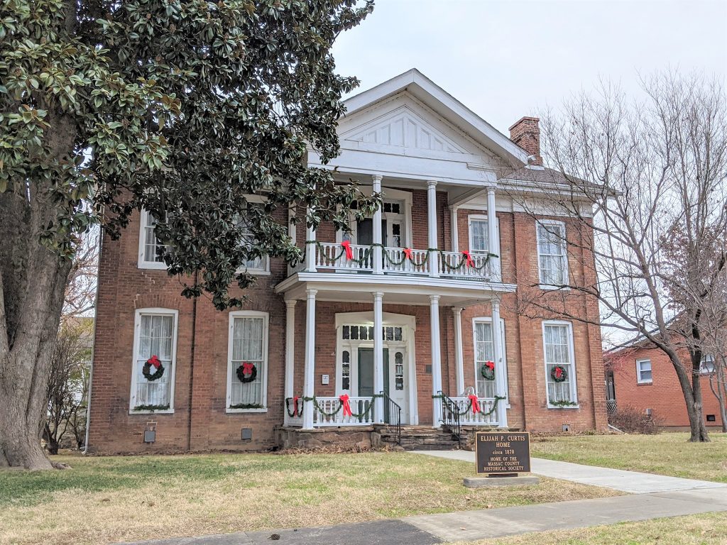 A large brick house with christmas wreaths on the windows.